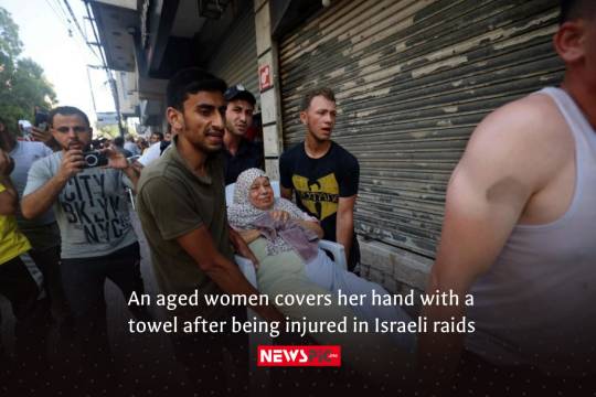 An aged women covers her hand with a towel after being injured in Israeli raids